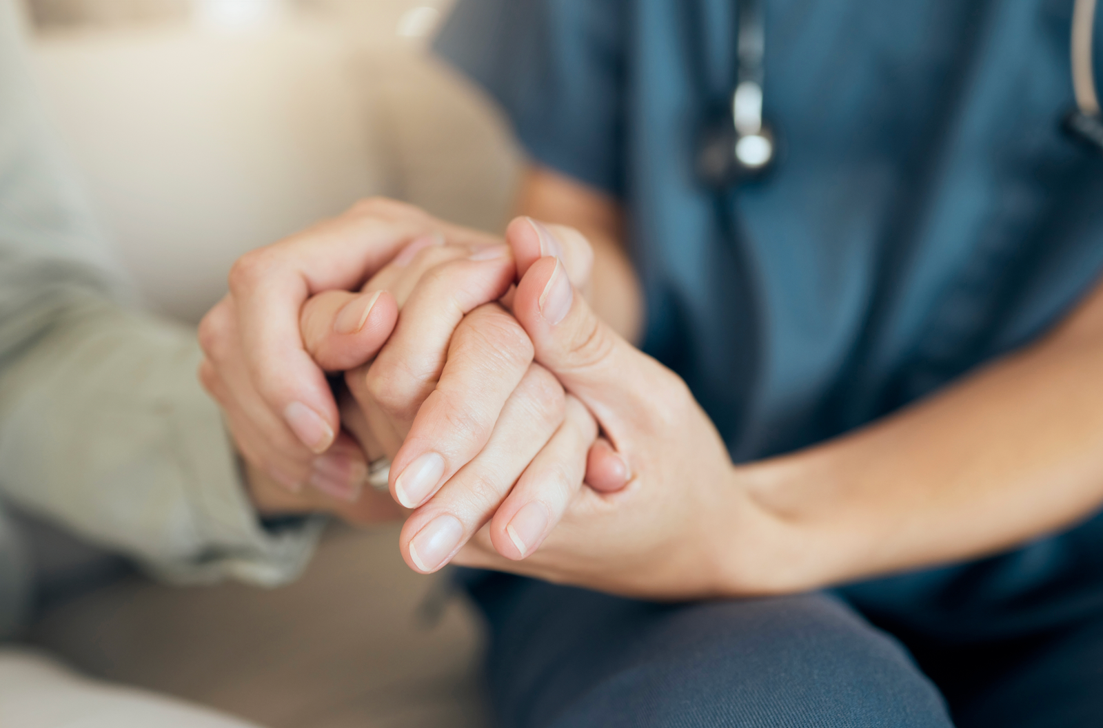 Private duty nurse holding patients hand for post-op visit at home for in-home care recovery.